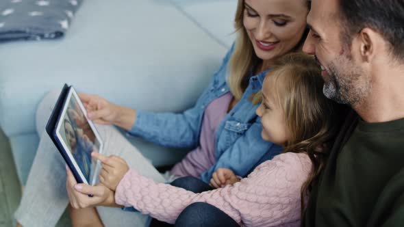 Parents with daughter watching photos on the tablet