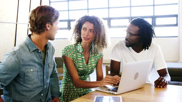 Colleagues discussing with each other over laptop