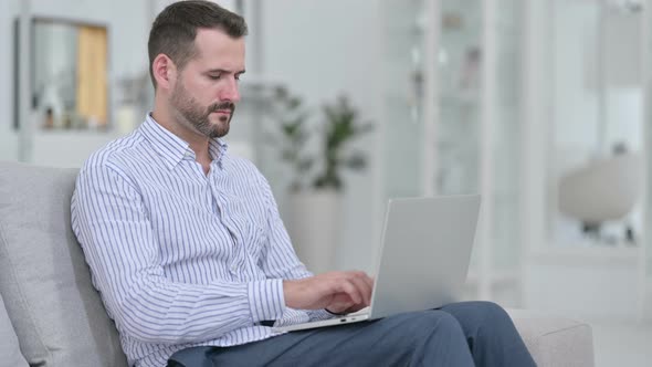 Stressed Young Man with Laptop Having Headache at Home 