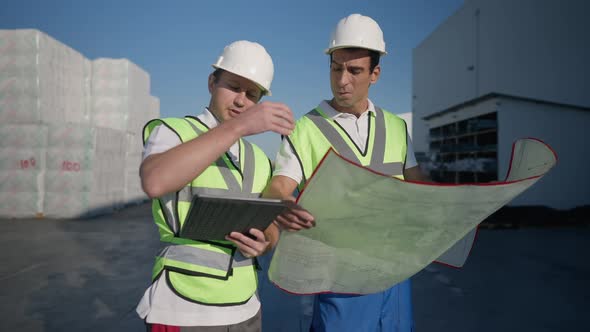 Male Caucasian Warehouse Manager Discussing Project with Middle Eastern Engineer in Slow Motion in