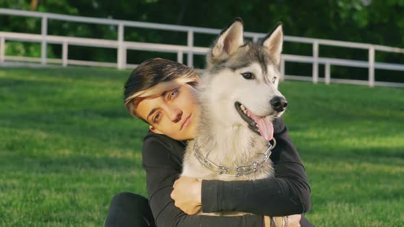 Beautiful Young Woman Playing with Funny Husky Dog Outdoors in Park