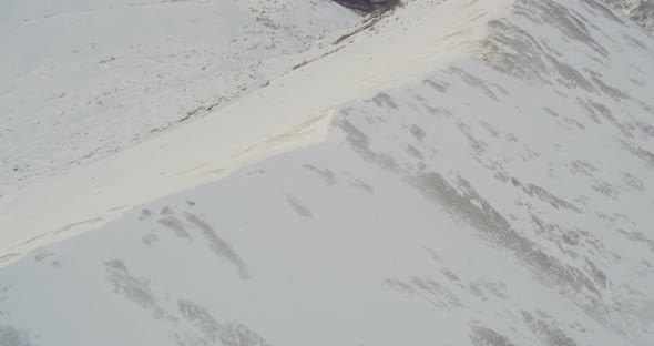 Aerial helicopter shot, above small snowy Alaskan road in suburban area, tilt up to see houses, hill