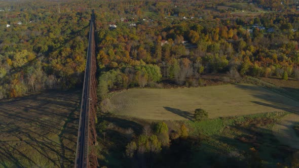 Aerial of railroad bridge over landscape and autumn forest