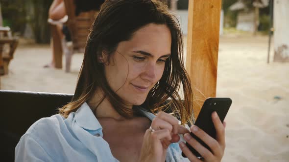 Beautiful Cinematic Shot of Happy Young Woman Using Smartphone E-commerce App Smiling, Relaxing