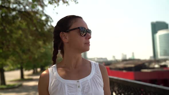 Close-up Portrait of a Middle-aged Woman with Dark Hair and Sunglasses, Walking Alone in a City Park