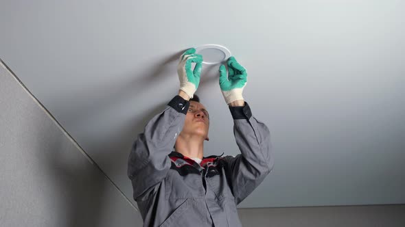 Electrician Installs Light on Ceiling at Flat Renovation