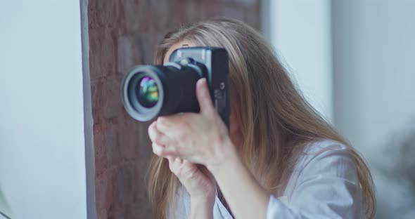 Beautiful Woman Photographer Makes Frames on a Professional Camera Looks Into the Lens