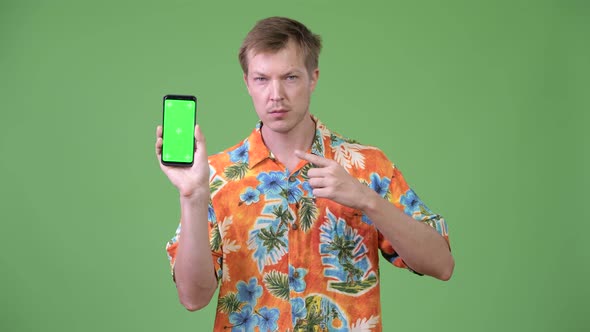 Young Handsome Tourist Man Showing Phone and Pointing Finger