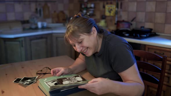 Middle aged woman looking at family photo album. Nostalgia, happines