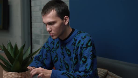 A Focused Young Man Working and Using His Laptop at Home or Office.