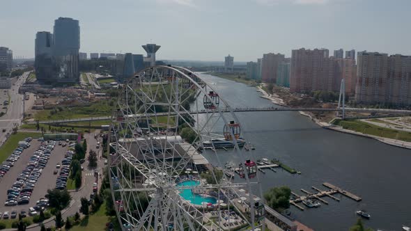 a Ferris Wheel on the River Bank with a Swimming Pool and a Beautiful Summer Landscape