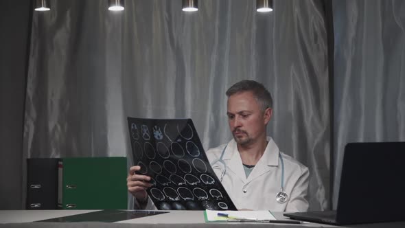 Medical Man Checking Roentgen Image in His Modern Office, Middle Aged Caucasian Doctor Sitting in