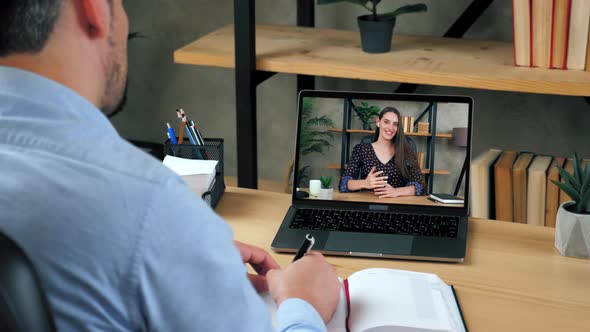 Man student study online by conference video call laptop, writes in notebook