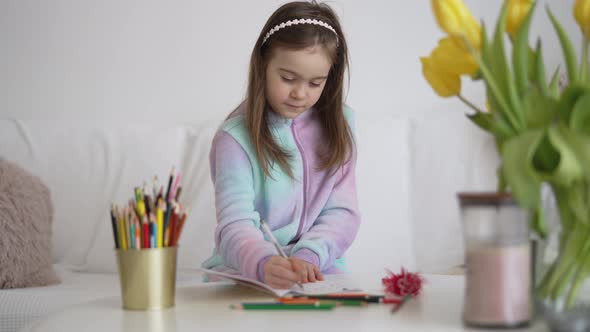 Girl Writing in Notepad Near Flowers