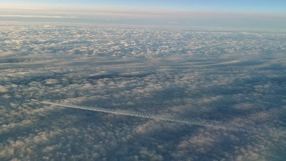 Incredible view from the cockpit of an airplane flying high above the clouds leaving a long white co