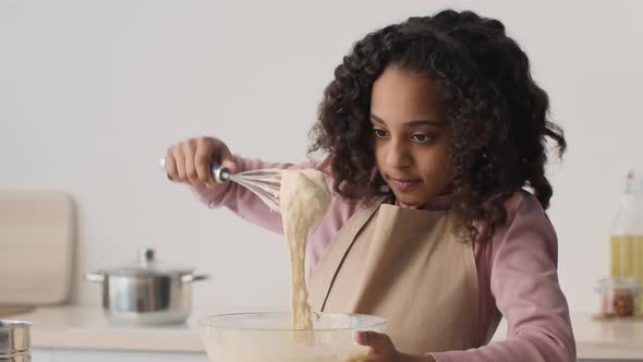 Cute African American Girl Playing with Raw Dough Watching It Pouring From Whisk at Kitchen Slow