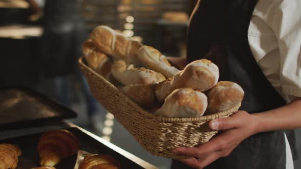 Animation of happy asian female baker holding basket with baguettes