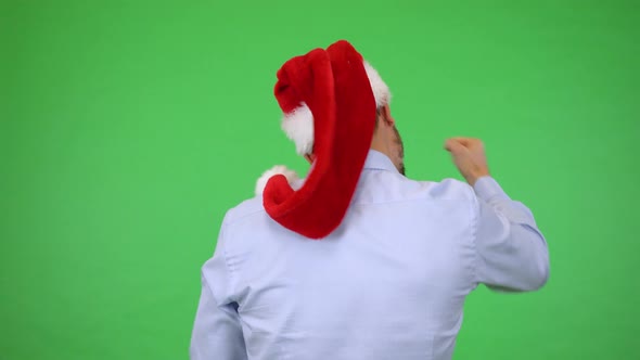 A Young Handsome Man in a Christmas Hat Cheers with His Back To the Camera - Green Screen Studio