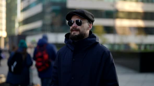 Casual Style Dressed Man with Cap and Sunglasses is Walking in City Center in Daytime