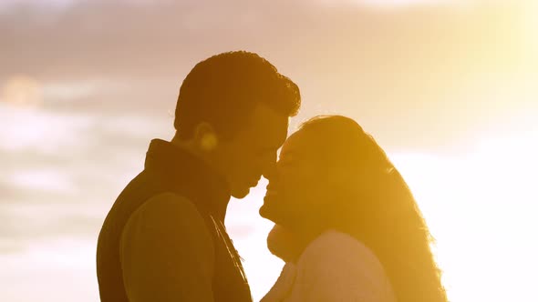 Happy couple walking on the beach at sunset