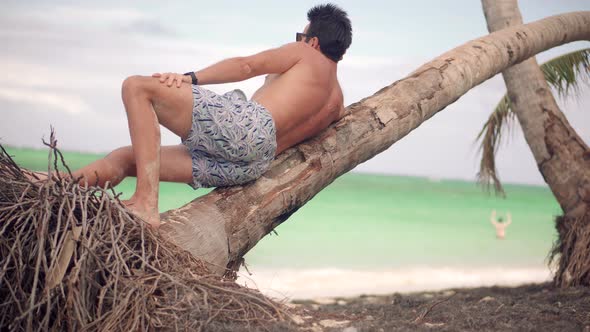 Man Sitting On Palm On Vacation.  Guy Resting On Coast Hotel Luxury. Tanned Man Relaxing Vacation.