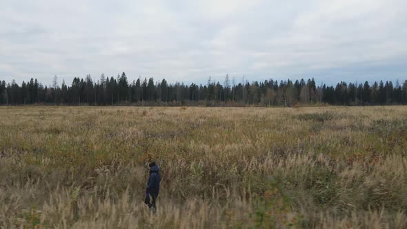 Woman in a Blue Jacket Walks Through an Autumn Field