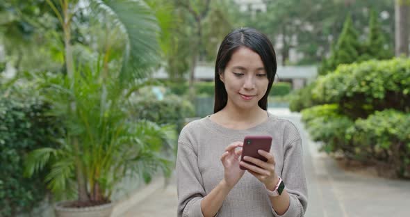 Woman work on mobile phone in city park