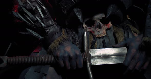 Close Up of the Hands of an Orc on the Sword with a Skull on His Belt, 