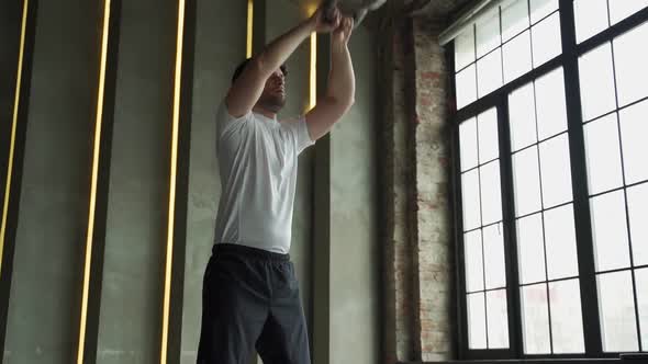 Athletic Man Lifts a Kettlebell Over His Head During a Workout at the Gym