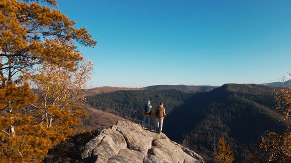 Aerial Footage Couple Hikers Standing on Top of Cliff with Raised Arms