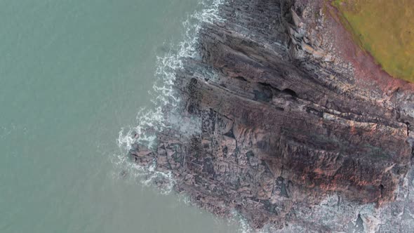 AERIAL: Top down fly along jagged rock coastline, Rhossili Gower, 4k Drone