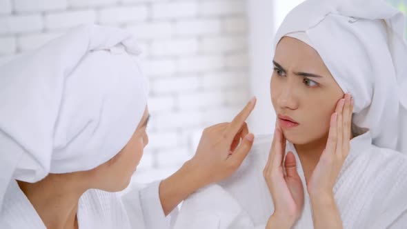 Two Asian girls in white bathrobes with towels on heads talking in living room.