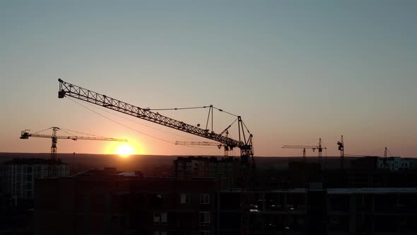 Aerial Drone View of Construction Cranes in Sunset Light. Construction Site Building in City