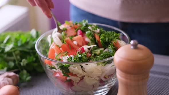 Woman Mixes a Salad of Vegetables in Glass Bowl  Tomatoes Cucumbers Onion Parsley