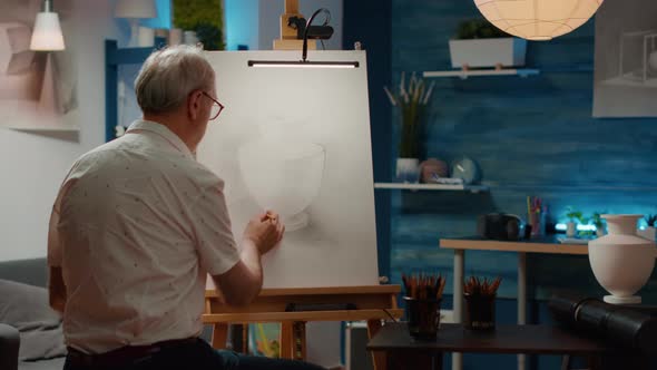 Senior Man Looking at Vase Design Inspiration to Draw Sketch