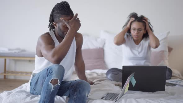 Depressed Sad African American Man Holding Head in Hands As Blurred Woman Arguing Yelling Gesturing