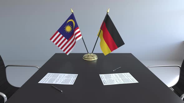 Flags of Malaysia and Germany and Papers on the Table