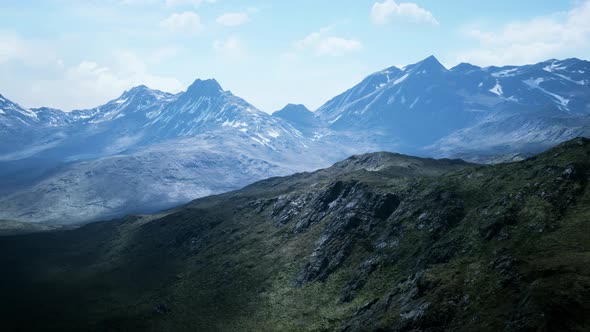 Aerial Over Valley With Snow Capped Mountains In Distance