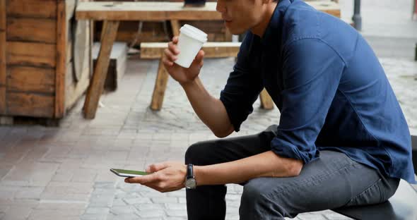 Man having coffee while using mobile phone 