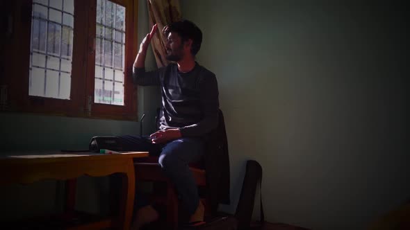 Lone Man Sitting By The Window And Looking Outside On A Sunny Morning