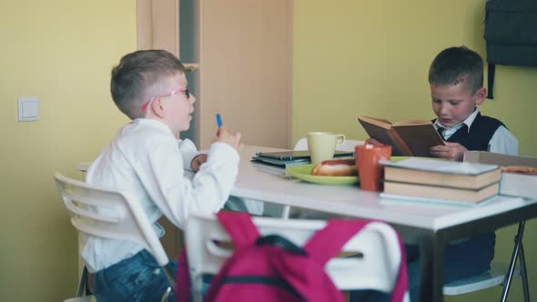 Schoolboys with Snacks and Textbooks Sit at Table in Canteen