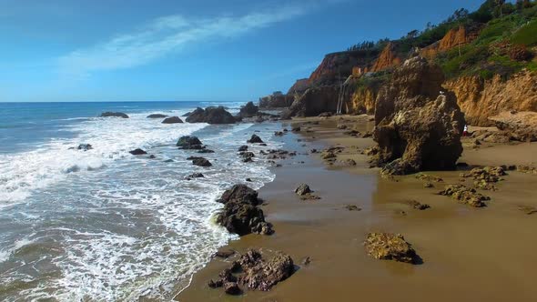 Aerial camera moving over rocks and waves at El Matador Beach Malibu, Califronia, USA