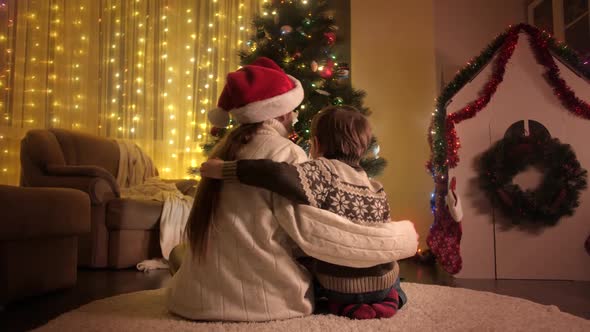 Rear View of Boy and Mother Hugging Under Christmas Tree in Living Room