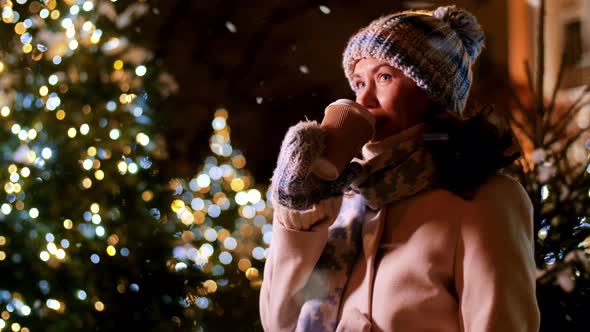 Happy Woman Drinking Coffee Over Christmas Lights