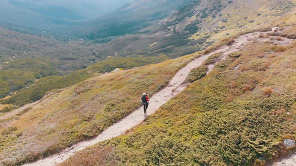 Aerial View of a Traveler with Backpack Climbing Along Mountain Slope. Epic Shot