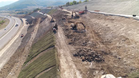 Construction machinery at work. Aerial drone shot, sidehill cut.