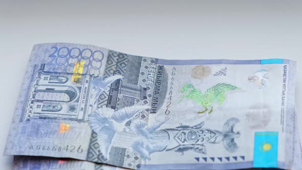 Man recalculates banknotes of Republic of Kazakhstan tenge, five, ten twenty thousand denominations.