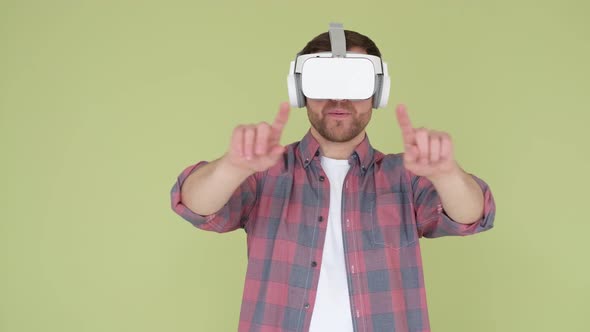 Handsome Man in Virtual Reality Glasses Studio on Yellow and Green Background