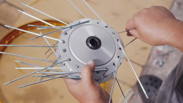 Technician man working motorcycle wheel has spokes weave up on mechanic new steel wheel