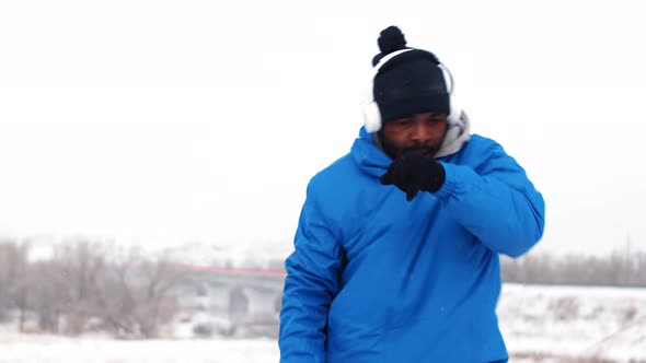 Black Man at Jacket Boxing Training Punches Outdoors in Winter Front View